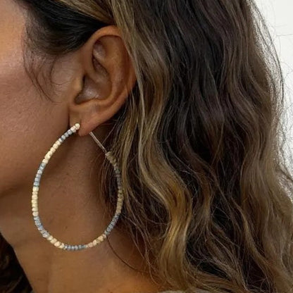 Woman wearing large hoop earrings with a neutral background