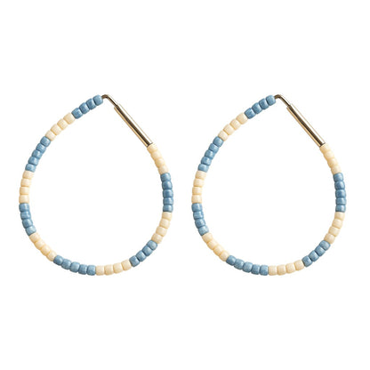Pair of hoop earrings with blue and beige beads on a white background