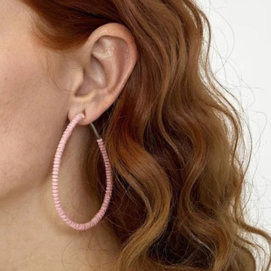 Woman with pink hoop earrings on a plain background